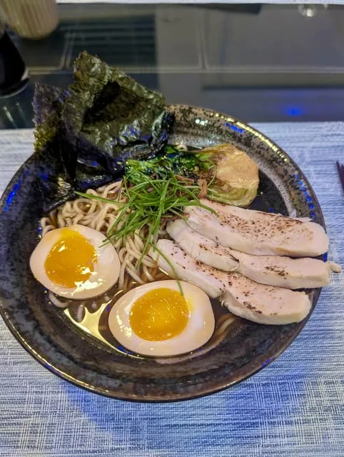 Shoyu ramen topped with sliced meat, soft-boiled eggs, greens, and nori