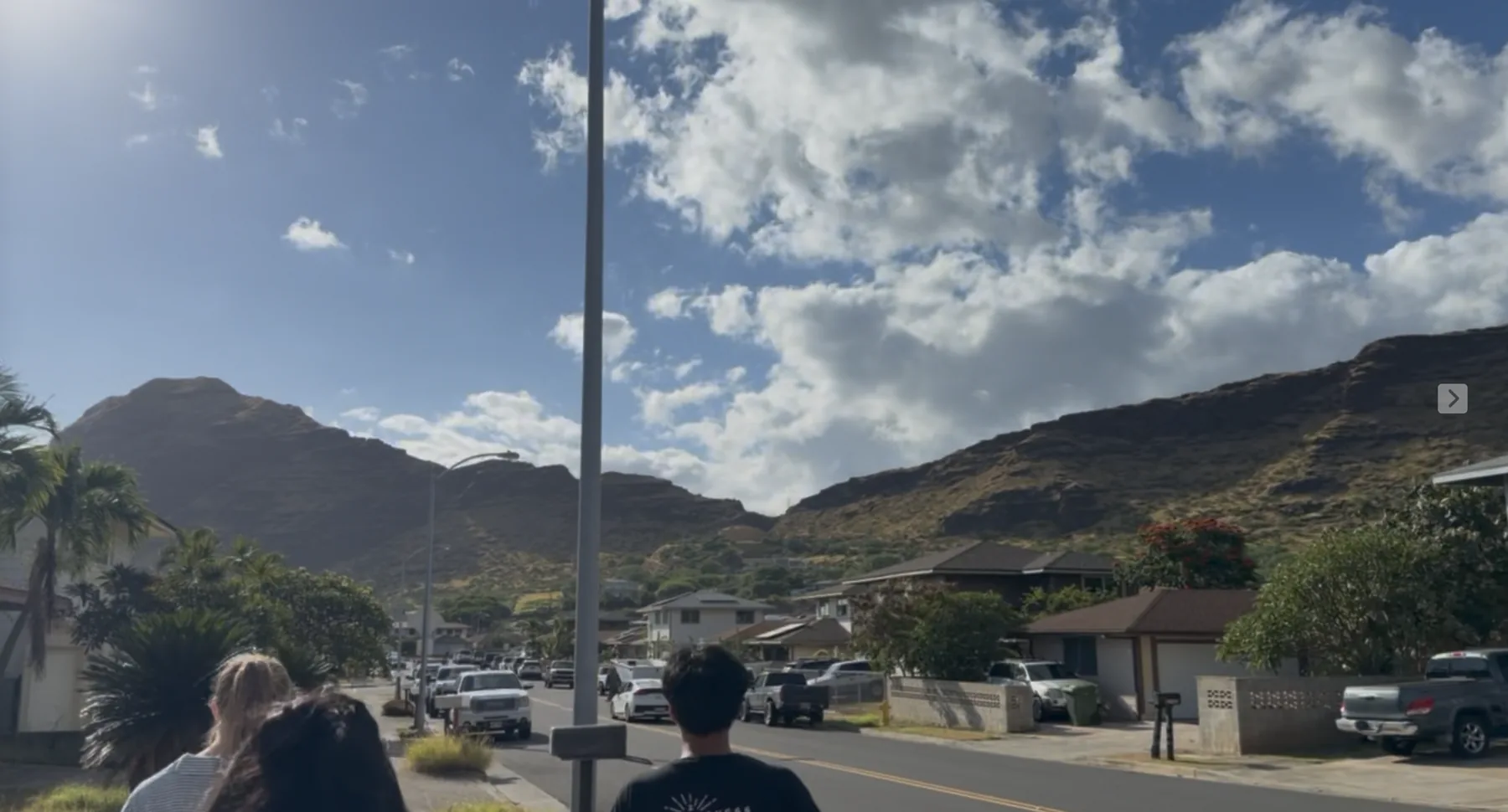 Team members walking through a Waiʻanae neighborhood with mountains behind them.