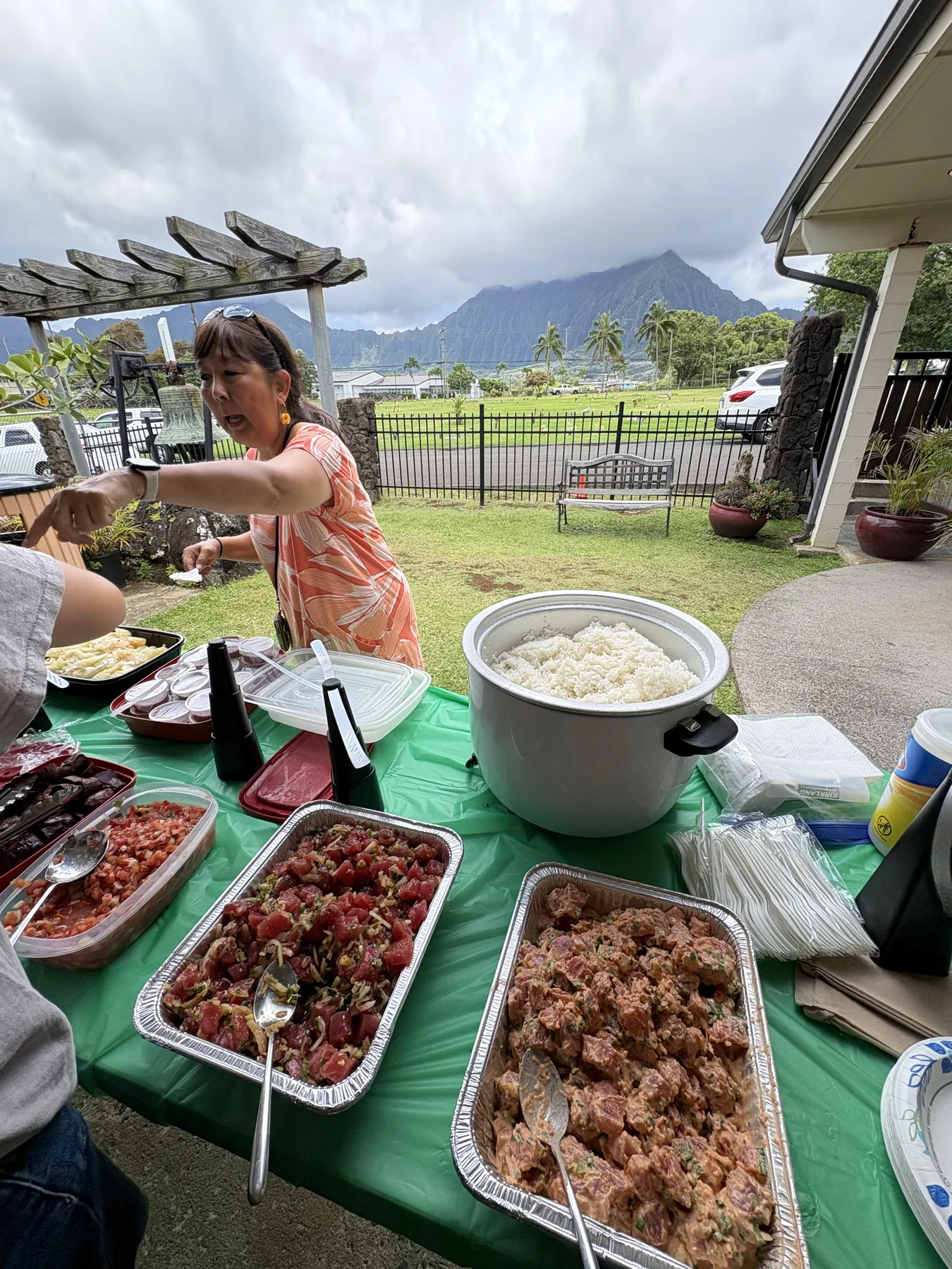 Traditional Hawaiian food table with poke, rice, and lau lau outside the church.