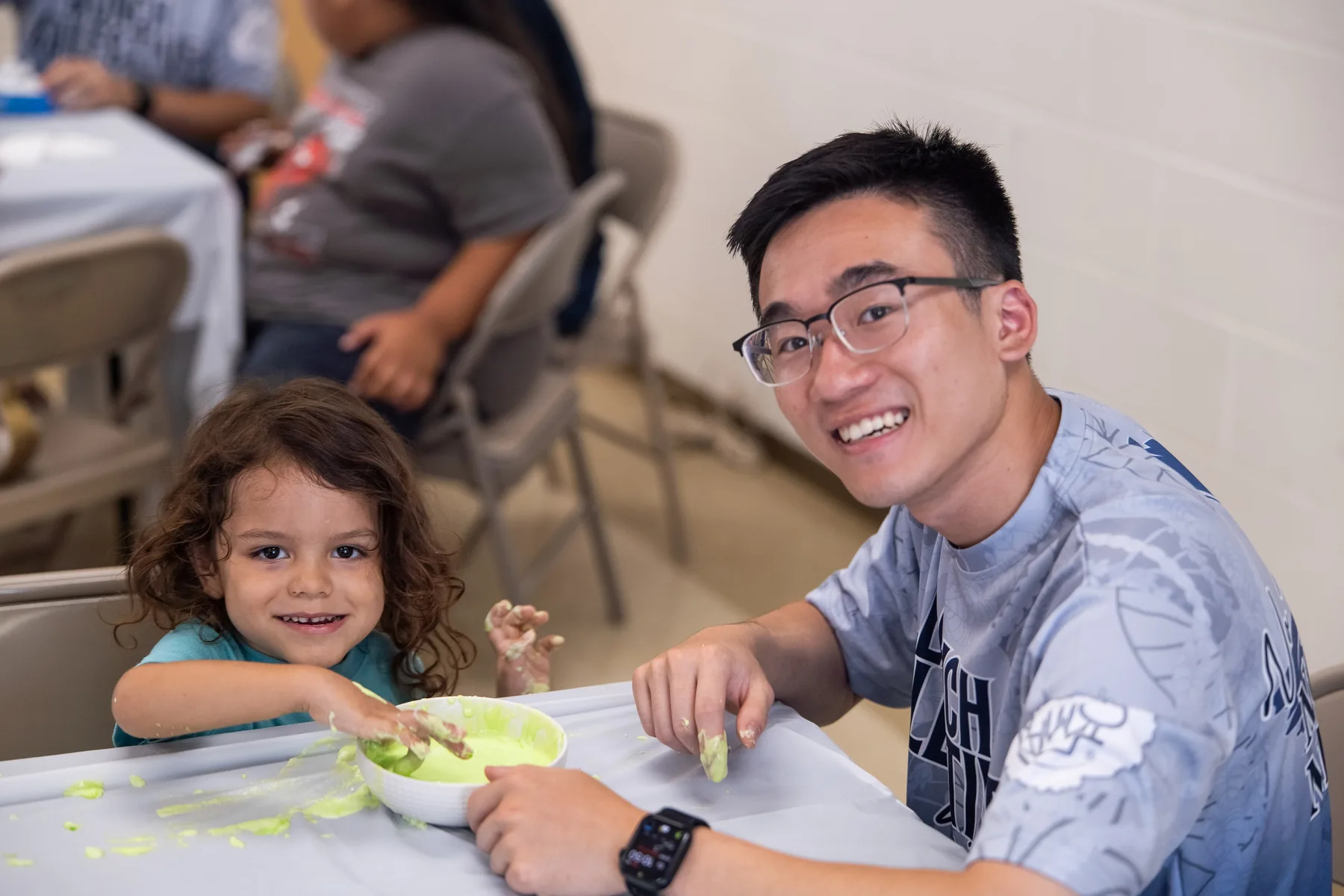 Michael sitting with a child during the slime-making activity.