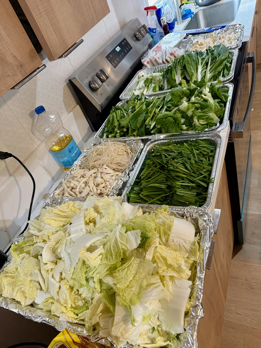 Hotpot vegetables and ingredients laid out in foil trays before dinner.