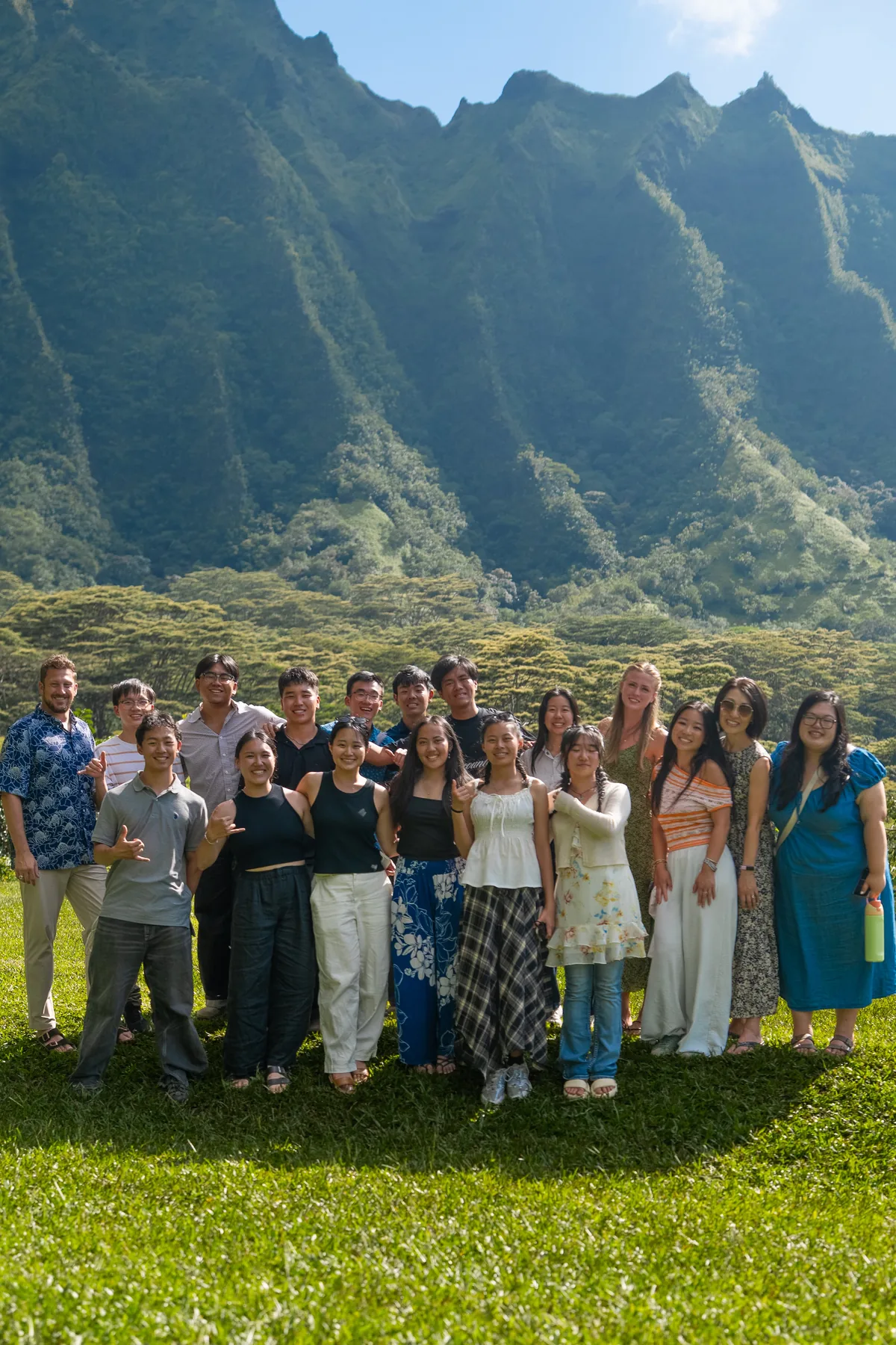 Large team photo in front of the green mountain backdrop.