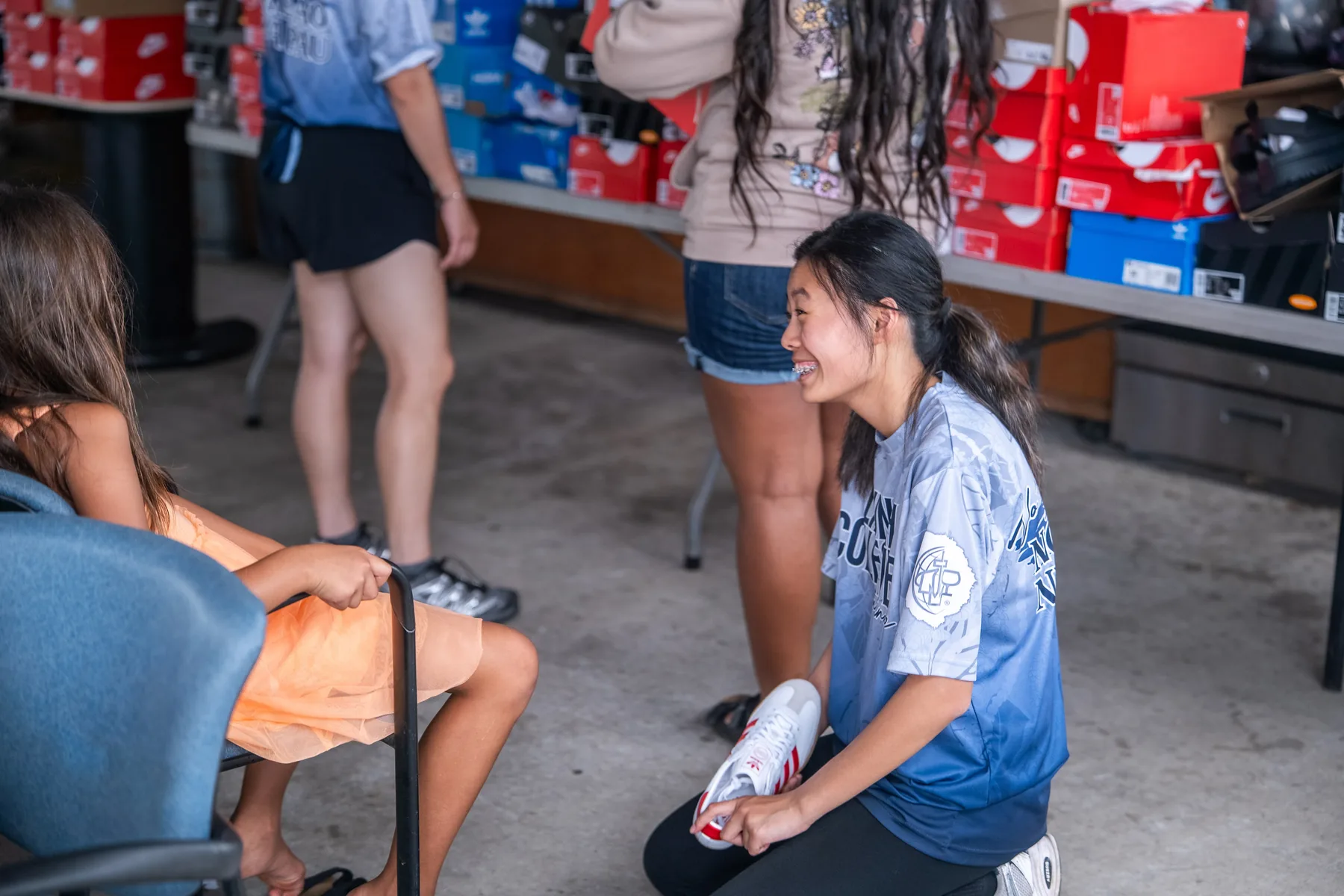 Team member kneeling to help a child with shoes.