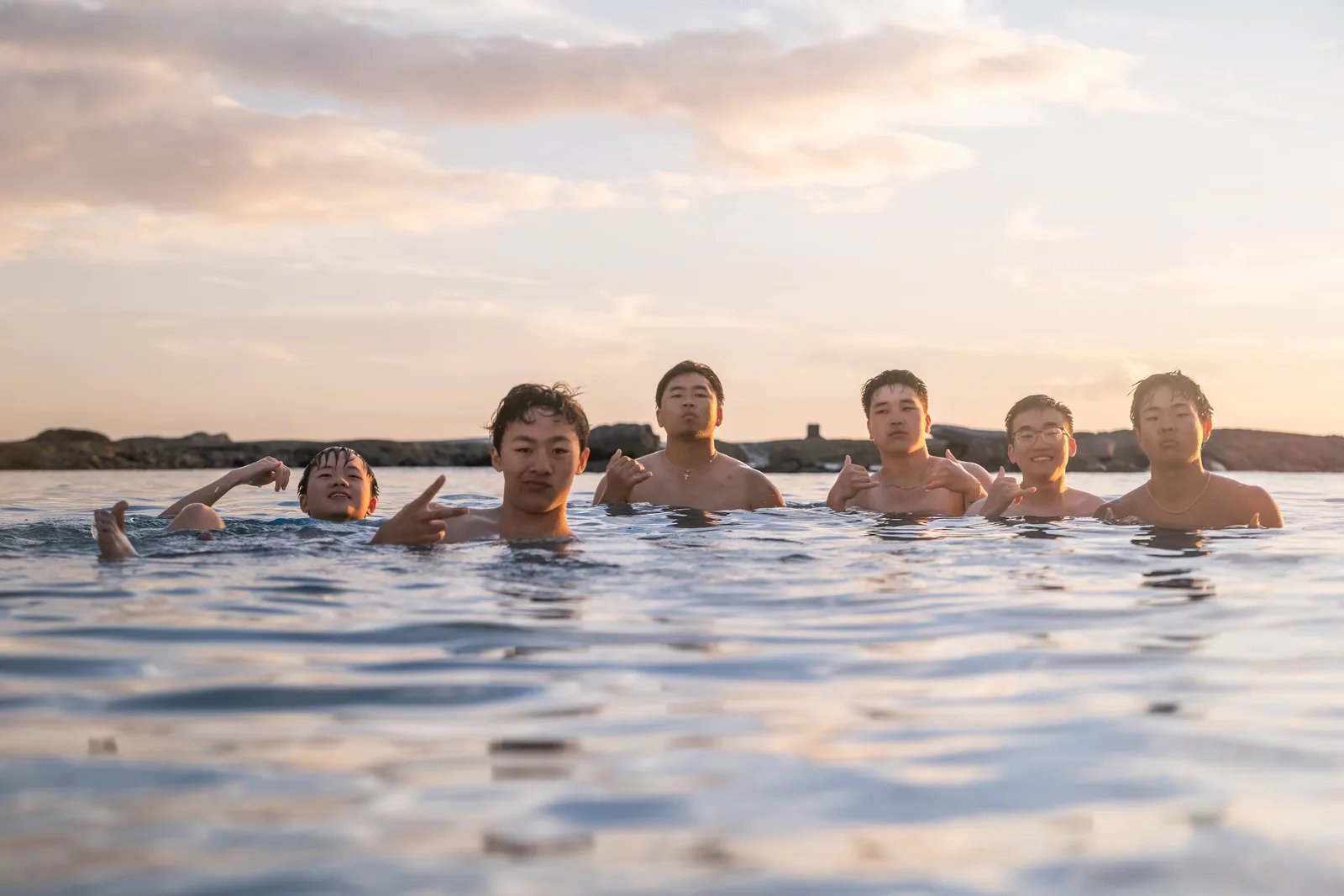 The boys posing in the ocean during golden hour.